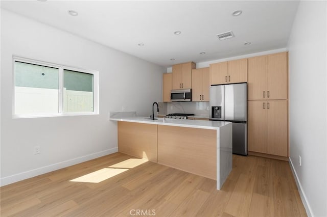 4641 W 130th St, Hawthorne, CA 90250 - kitchen with appliances with stainless steel finishes, light brown cabinetry, a peninsula, light wood finished floors, and light countertops