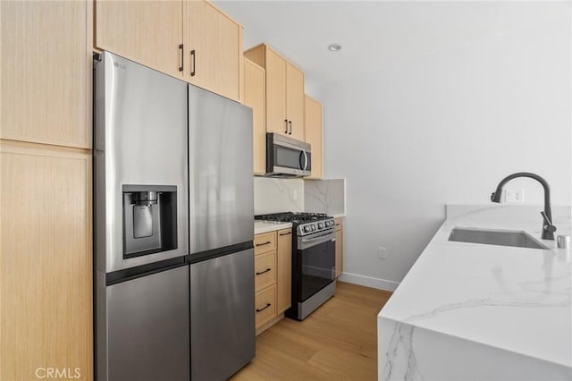 4641 W 130th St, Hawthorne, CA 90250 - kitchen with stainless steel appliances, light brown cabinetry, a sink, light wood-style floors, and tasteful backsplash
