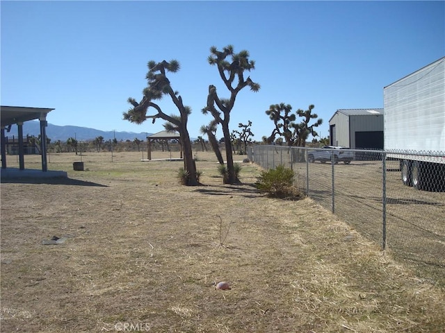 view of yard with an outbuilding, fence, a gazebo, and a mountain view