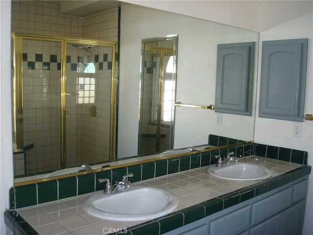 full bathroom with a shower stall, double vanity, and a sink