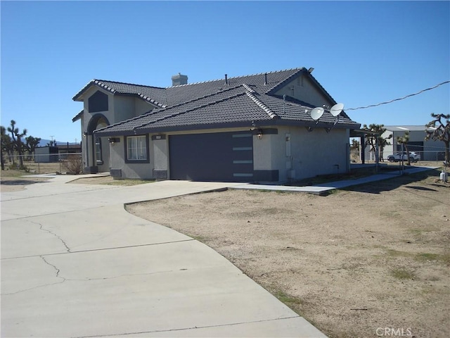 view of front of house with fence, a garage, concrete driveway, a tile roof, and stucco siding