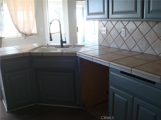 kitchen with tile counters, a sink, and tasteful backsplash