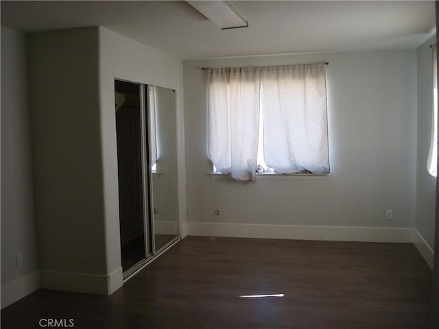 unfurnished bedroom featuring baseboards, a closet, and wood finished floors