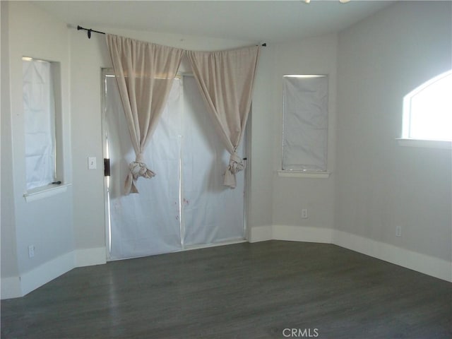 spare room featuring baseboards and wood finished floors