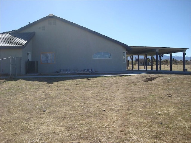 exterior space with central AC unit, a tile roof, and stucco siding