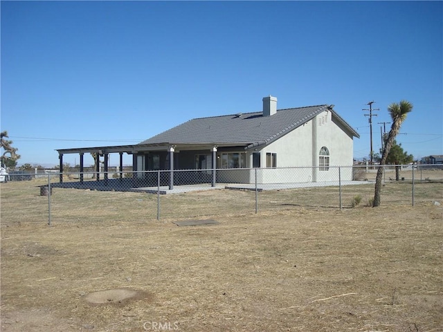 rear view of property featuring a tiled roof, stucco siding, fence, and a chimney
