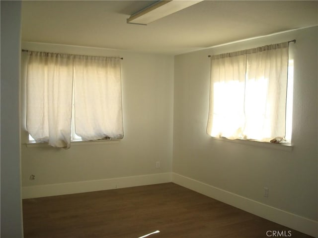 unfurnished room with dark wood-style flooring and baseboards
