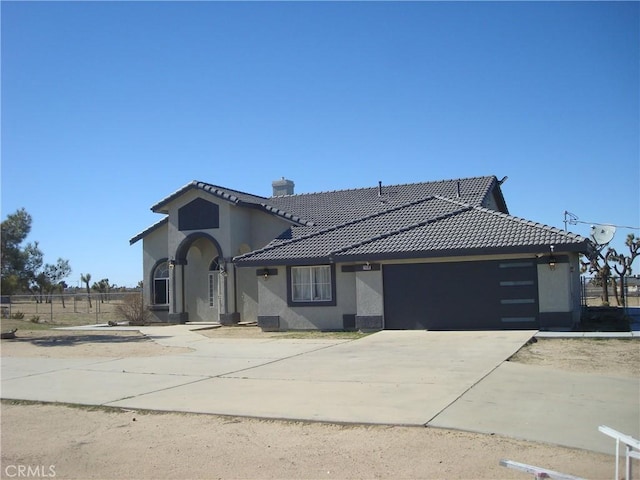 view of front of property featuring a tile roof, concrete driveway, a chimney, stucco siding, and an attached garage