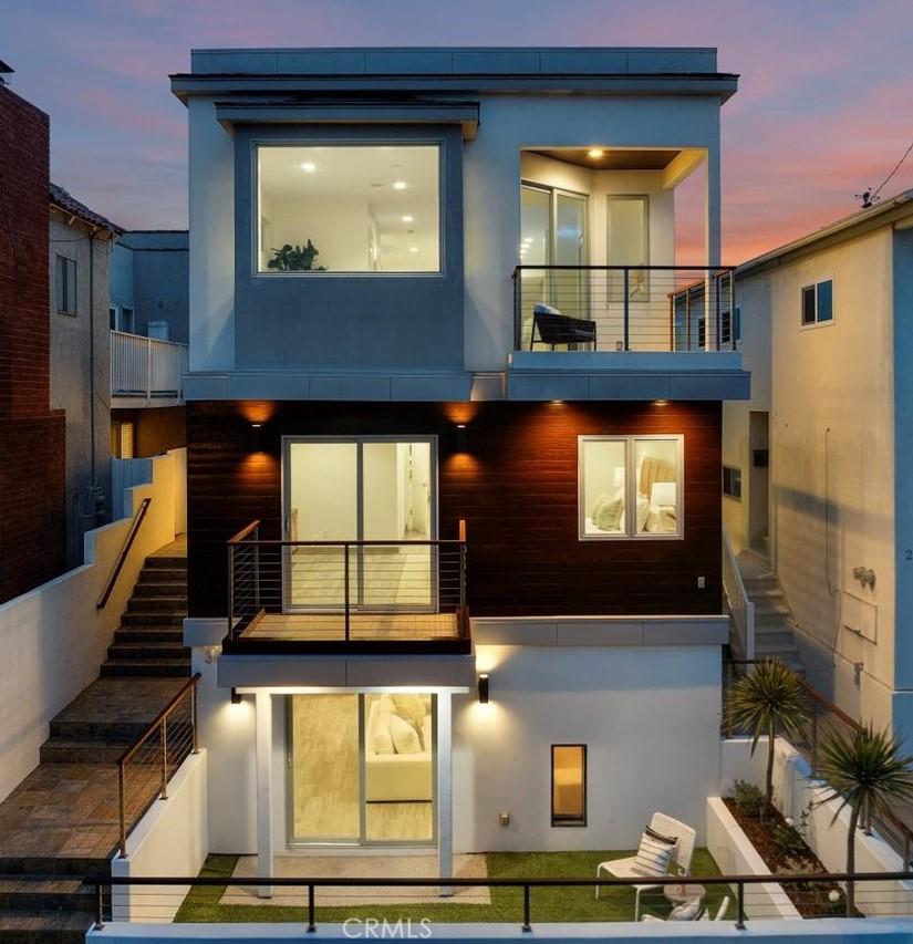 rear view of property with stucco siding, stairway, and a balcony