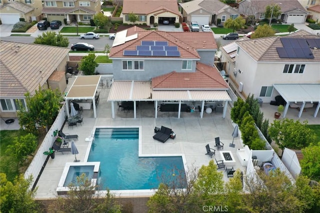 back of property with a pool with connected hot tub, a fenced backyard, a residential view, a patio, and outdoor dry bar