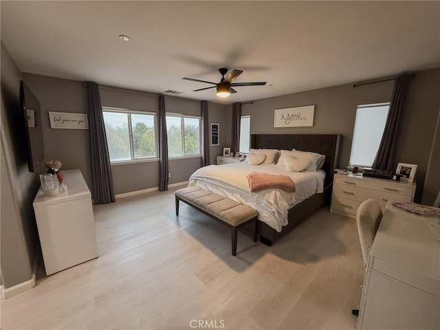 bedroom with baseboards, visible vents, light wood-style floors, and a ceiling fan