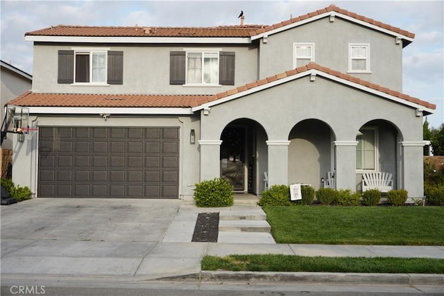 mediterranean / spanish home with a tile roof, a garage, and concrete driveway