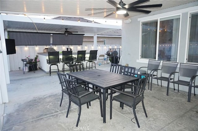 view of patio featuring fence, outdoor dining area, grilling area, outdoor dry bar, and a ceiling fan