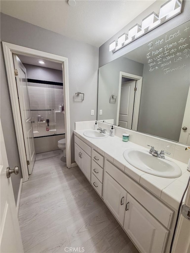 full bathroom with toilet, a sink, shower / bathtub combination, and double vanity