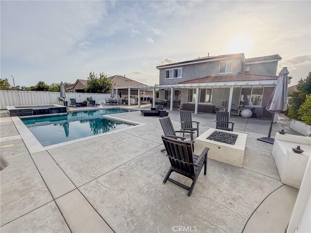 view of swimming pool featuring an outdoor fire pit, a pool with connected hot tub, fence, and a patio
