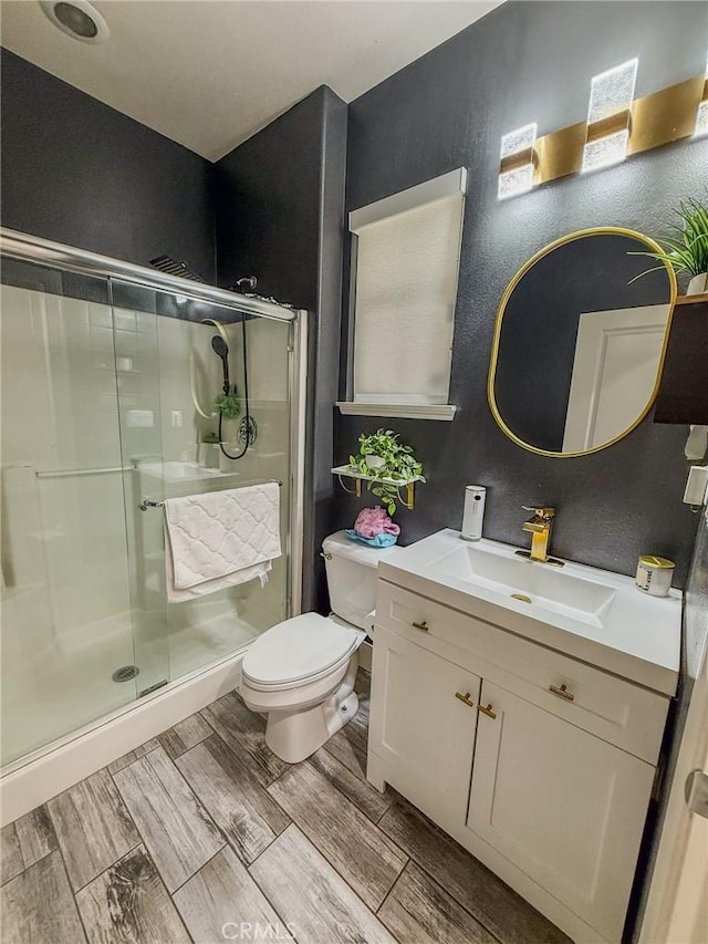 bathroom featuring wood finish floors, vanity, toilet, and a shower stall