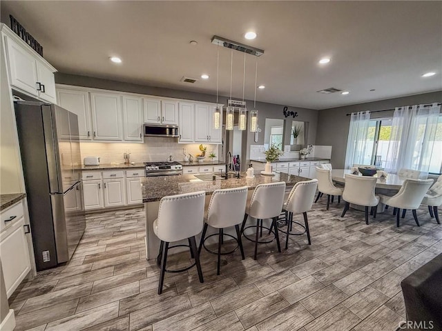 kitchen with range hood, a sink, visible vents, white cabinets, and appliances with stainless steel finishes