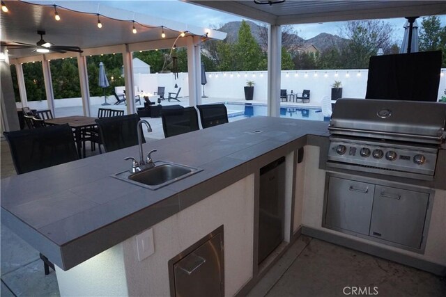 view of patio / terrace with exterior kitchen, outdoor dining space, a sink, outdoor wet bar, and area for grilling