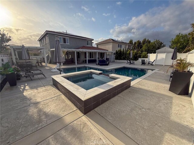 view of pool with a fenced backyard, a pool with connected hot tub, and a patio