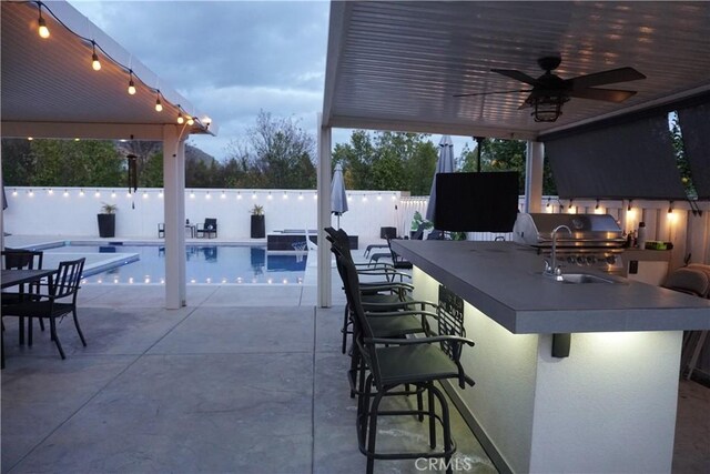 view of patio / terrace with area for grilling, a fenced in pool, a fenced backyard, outdoor wet bar, and an outdoor kitchen