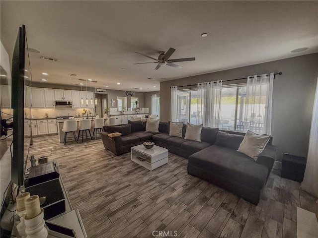 living room with wood finished floors, visible vents, recessed lighting, and ceiling fan