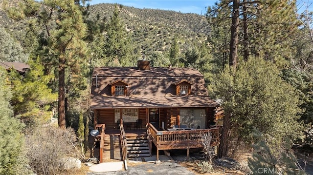 rustic home featuring log siding and a view of trees