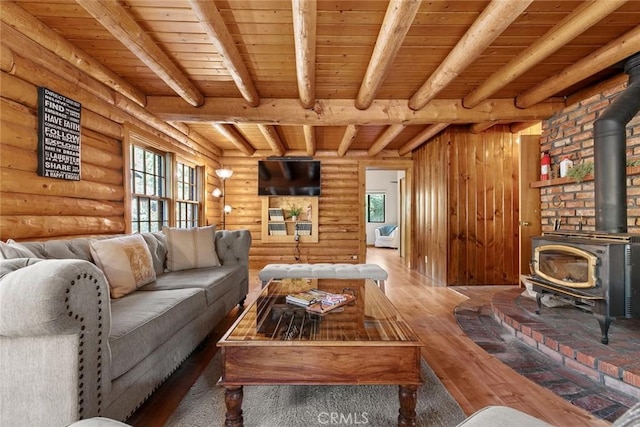 living area featuring hardwood / wood-style flooring, beam ceiling, a wood stove, and wood ceiling