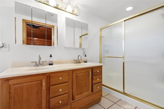 bathroom featuring a stall shower, tile patterned floors, double vanity, and a sink