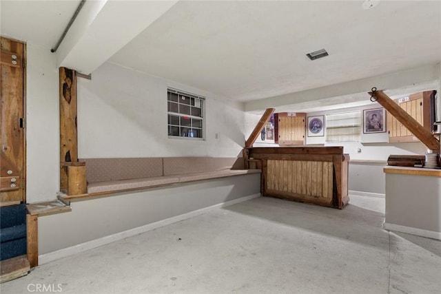 bar featuring baseboards, a dry bar, and unfinished concrete floors