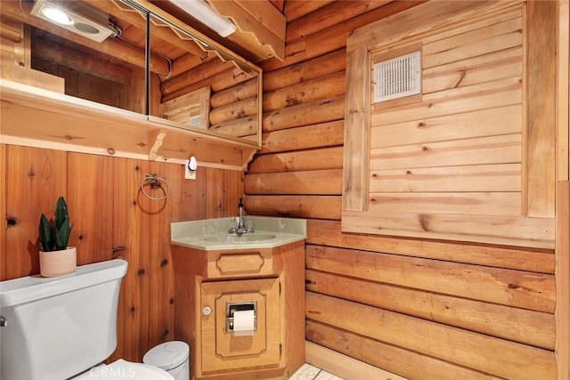 bathroom with toilet, rustic walls, and vanity