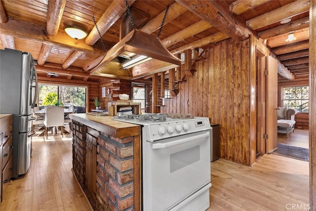 kitchen with white gas stove, light wood-type flooring, wooden ceiling, and freestanding refrigerator