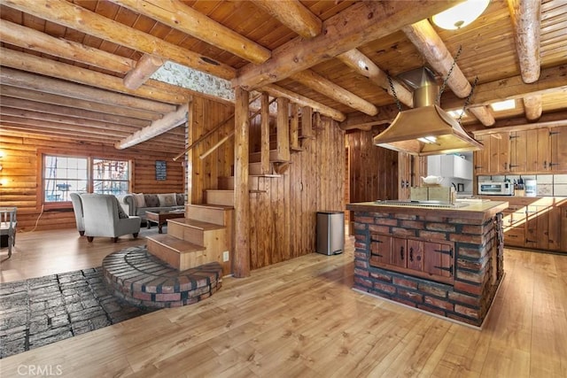 kitchen with beamed ceiling, light wood finished floors, an island with sink, open floor plan, and wood ceiling
