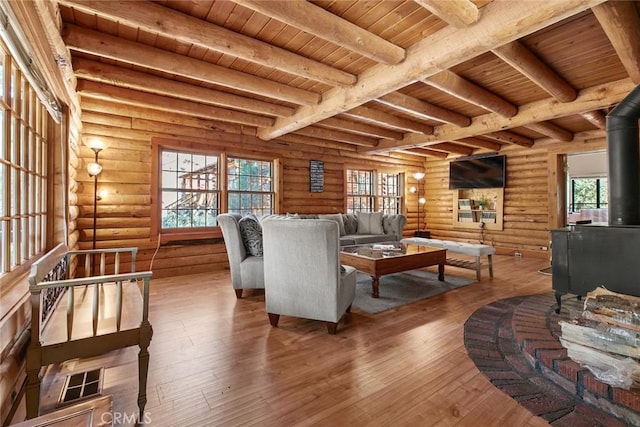 living room featuring wood-type flooring, wooden ceiling, beamed ceiling, and a wood stove