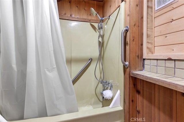 full bathroom featuring shower / bath combination with curtain, wood walls, and decorative backsplash