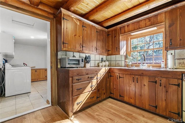kitchen with decorative backsplash, a toaster, beam ceiling, brown cabinetry, and washer / dryer