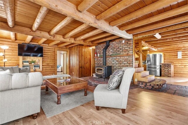 living area featuring wood finished floors, wooden ceiling, beam ceiling, and a wood stove