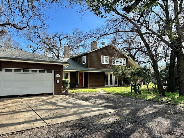 view of front facade featuring a chimney, a garage, and concrete driveway