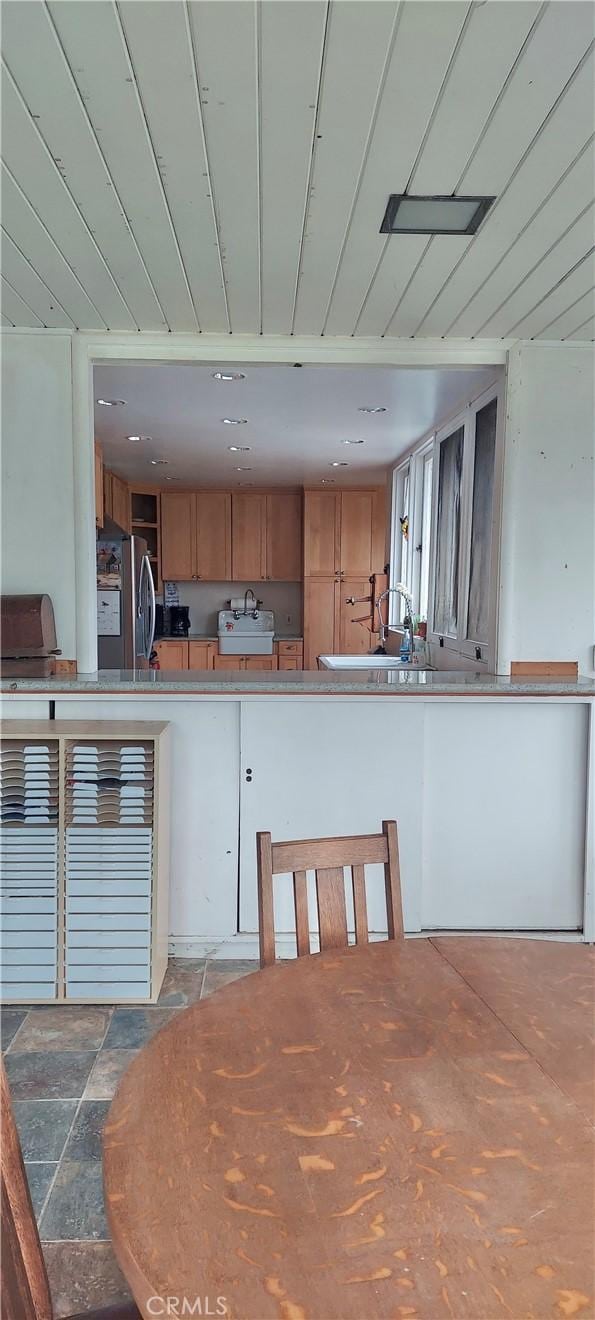 kitchen with brown cabinetry and freestanding refrigerator