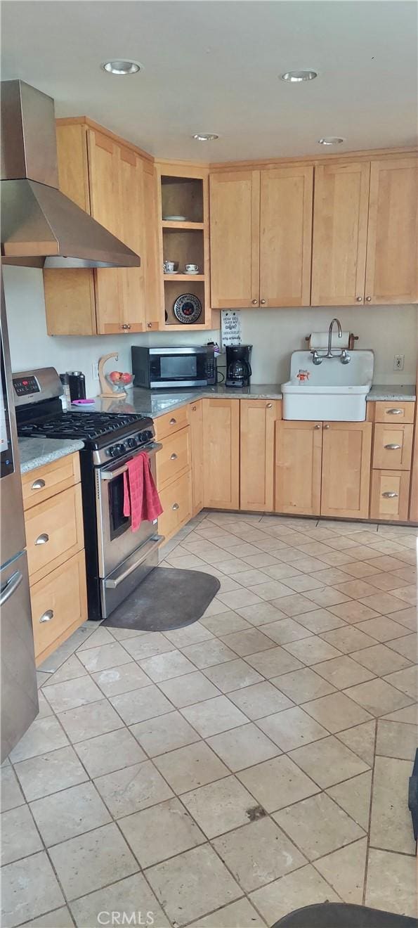 kitchen featuring open shelves, stainless steel appliances, light brown cabinetry, a sink, and wall chimney range hood