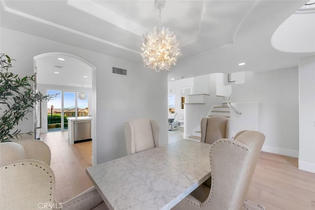 7 Suprema Dr, Newport Coast, CA 92657 - dining space featuring light wood-style flooring, arched walkways, a chandelier, a raised ceiling, and recessed lighting