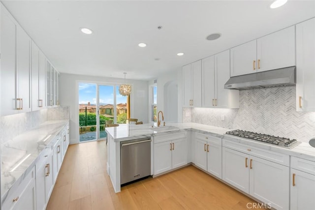 7 Suprema Dr, Newport Coast, CA 92657 - kitchen featuring appliances with stainless steel finishes, under cabinet range hood, white cabinetry, tasteful backsplash, and light stone countertops