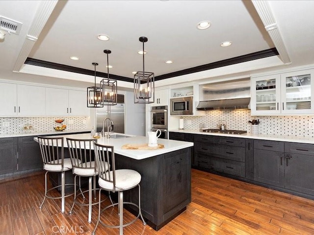 2565 Cliff Rd, Upland, CA 91784 - kitchen with built in appliances, a tray ceiling, a kitchen breakfast bar, light countertops, and a kitchen island with sink