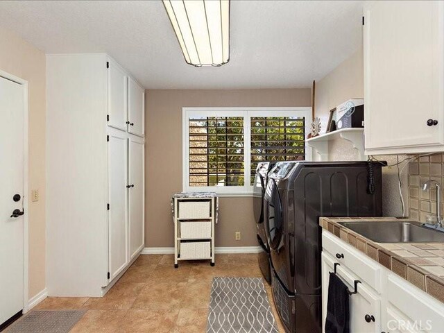 2565 Cliff Rd, Upland, CA 91784 - washroom featuring washing machine and clothes dryer, a sink, cabinet space, and baseboards