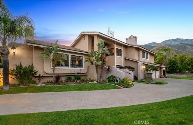 2565 Cliff Rd, Upland, CA 91784 - view of front facade featuring curved driveway, stucco siding, a chimney, a garage, and a mountain view