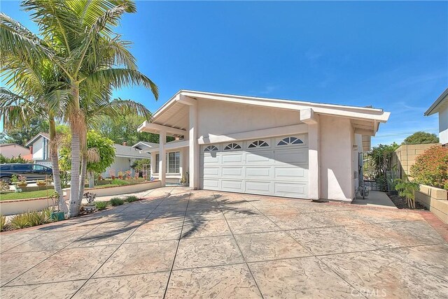 view of front of property featuring stucco siding, driveway, fence, and an attached garage
