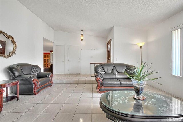 living room with a textured ceiling, light tile patterned floors, and vaulted ceiling