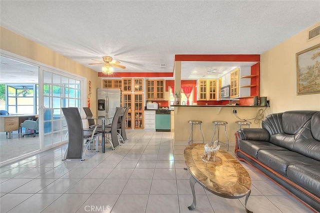 living room featuring ceiling fan, a textured ceiling, and light tile patterned floors