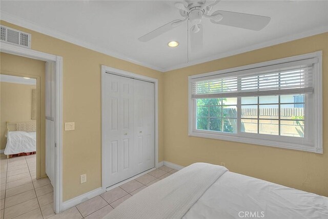 bedroom featuring light tile patterned floors, baseboards, ornamental molding, a closet, and a ceiling fan
