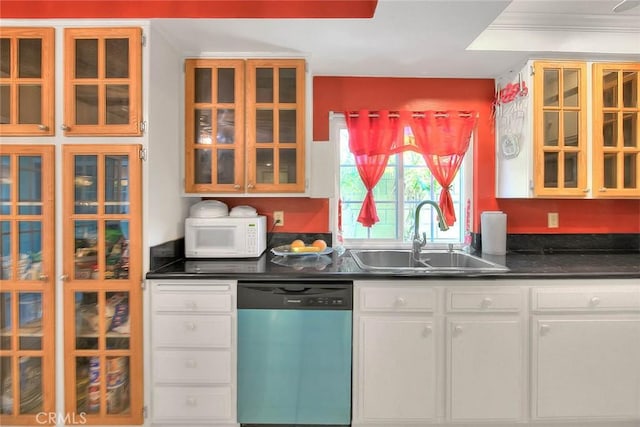 kitchen featuring dishwashing machine, a sink, white microwave, dark countertops, and white cabinetry