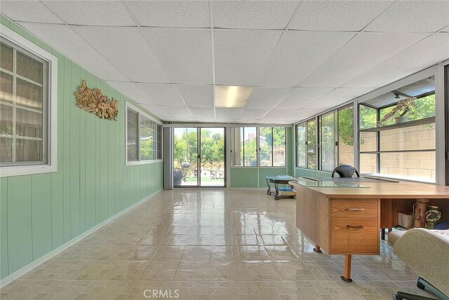 sunroom featuring a drop ceiling and baseboards